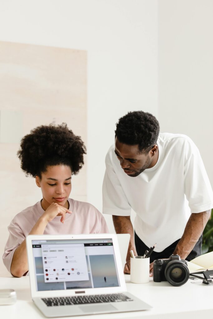 Two coworkers discussing project details over a laptop in a modern office setting.