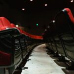 Close-up of empty red upholstered seats in a dimly lit theater interior.